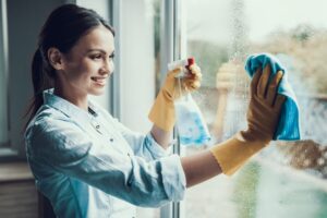 moça limpando a janela com produtos de limpeza sustentáveis adquiridos online
